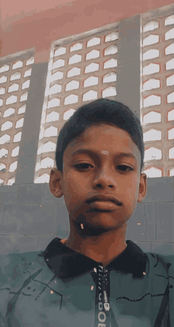 a boy wearing a green shirt with the word cool on the zipper