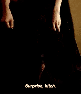 a woman in a black dress is talking to a man and says surprise bitch .