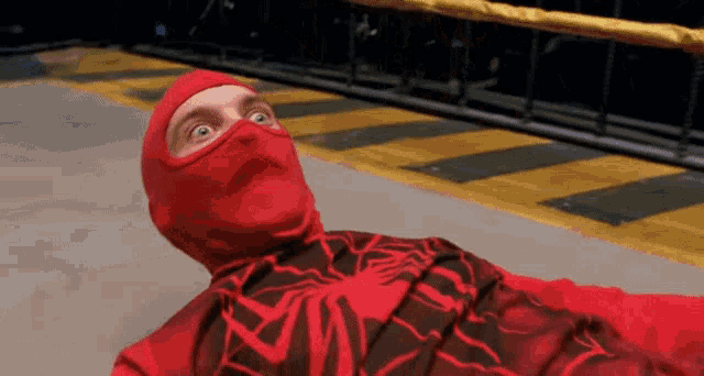 a man in a red spiderman costume is laying on the floor