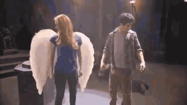 a man and a woman are standing next to each other with angel wings on .