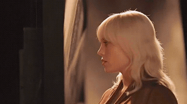 a woman with blonde hair is standing in front of a mirror and looking at herself in the mirror .