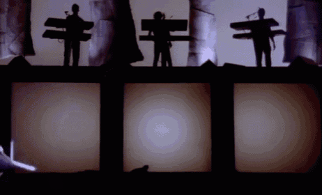 a group of people standing on top of a stage with their shadows on the wall
