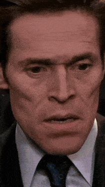 a close up of a man 's face wearing a suit and tie .