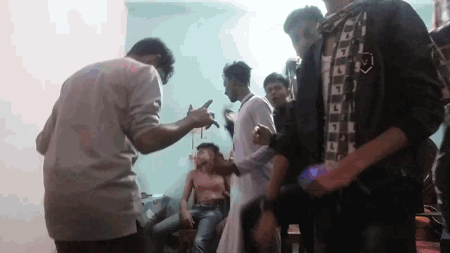 a group of young men are dancing in a room with a man without a shirt on