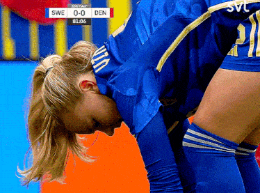 a female soccer player looks down at the scoreboard for swe 0-0 den
