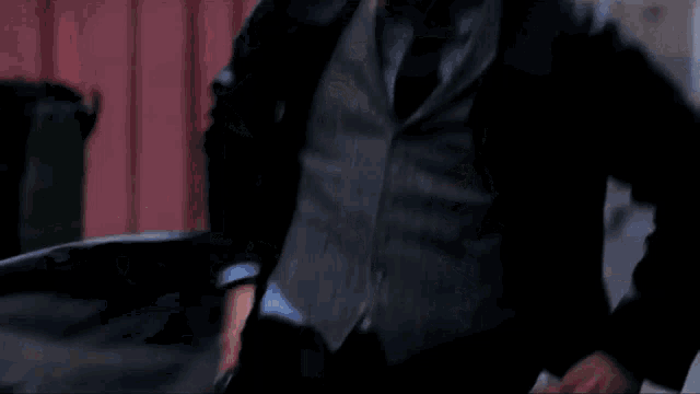 a man in a suit and tie is walking down a street in front of a building