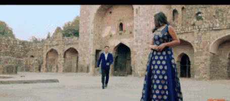 a man and a woman are standing next to each other in front of a stone building .