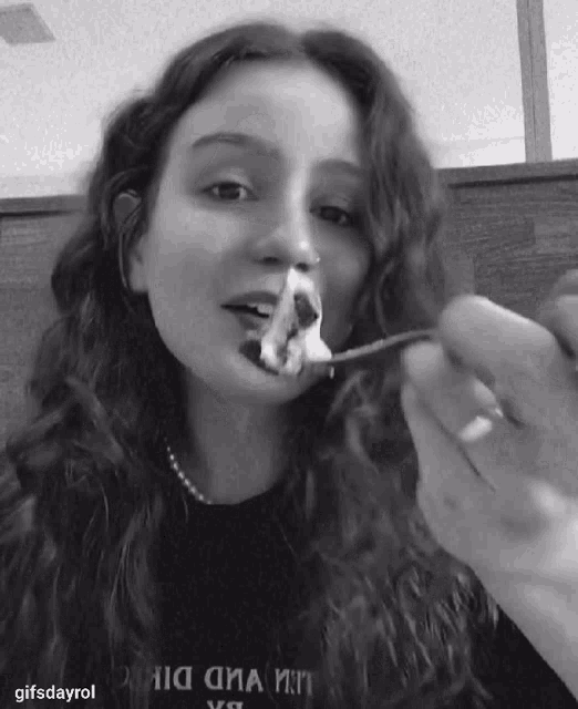 a black and white photo of a woman eating food with the caption gifsdayrol on the bottom