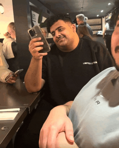 a man wearing a black shirt that says limited edition is holding a cell phone