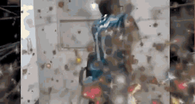 a man in a blue shirt is standing in a room with a lot of dust on the wall .