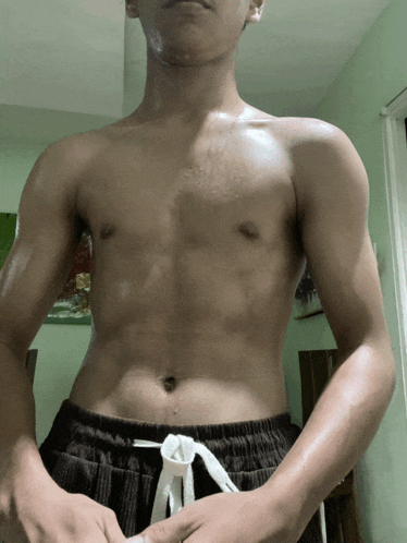 a shirtless man is standing in a room with his hands on his hips