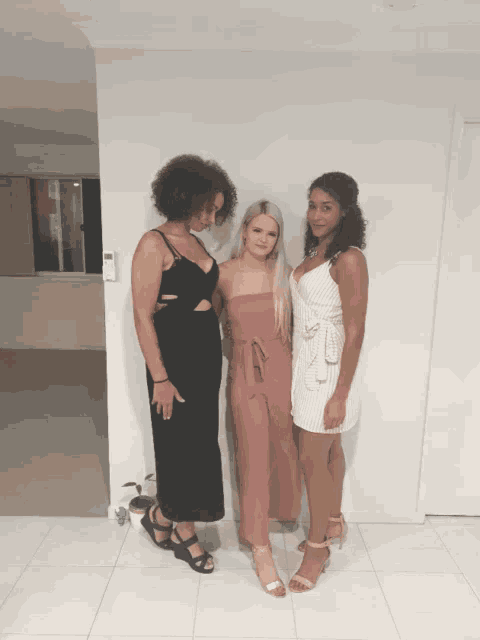 three women are posing for a picture and one is wearing a black dress