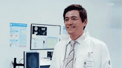 a man in a lab coat and tie is making a funny face in a lab .