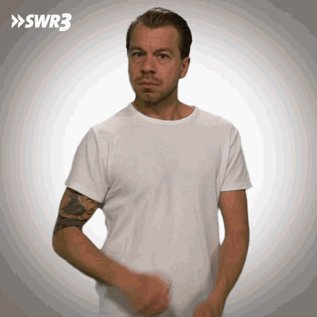 a man with a tattoo on his arm is wearing a white t-shirt with the letters swr3 on the bottom