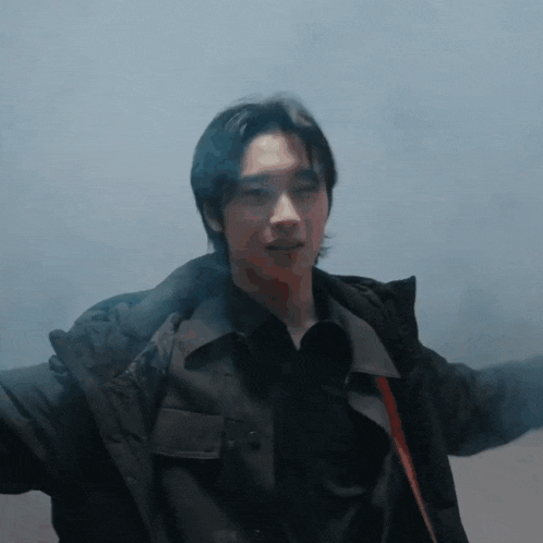 a man in a black jacket is standing in a room with smoke coming out of his jacket
