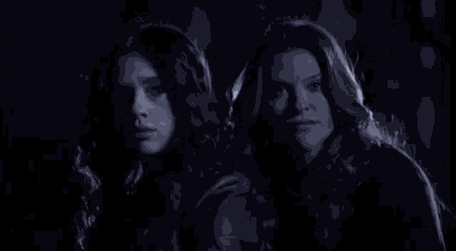 two women are standing next to each other in the dark in a dark room .