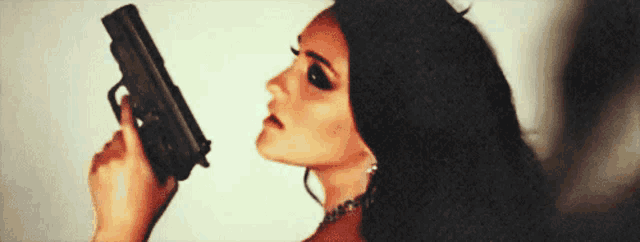 a woman with long dark hair is holding a gun
