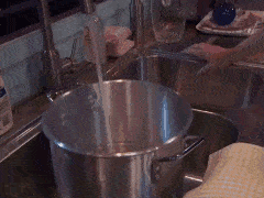 a man is pouring hot sauce into a pot on a stove