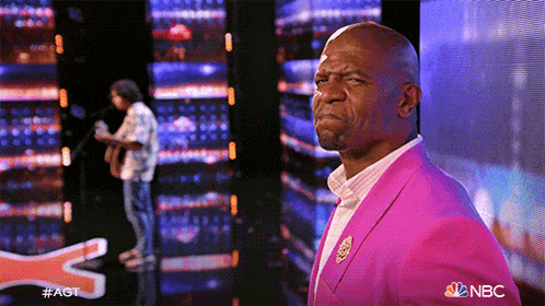 a man in a pink suit stands on a stage in front of a screen that says nbc