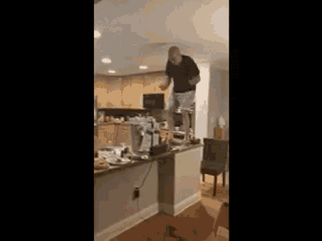 a man is standing on a counter in a kitchen