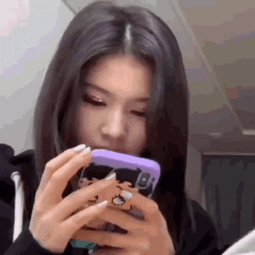 a woman is holding a purple cell phone in her hands .