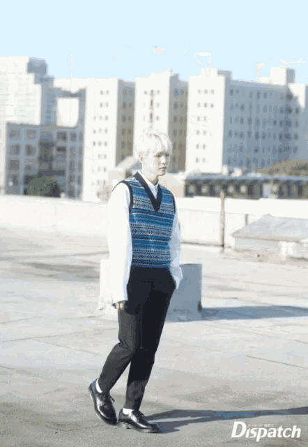 a man wearing a blue and white vest and black pants is walking in front of a building that says dispatch on it