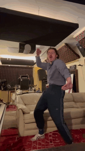 a man is dancing in a living room with a couch