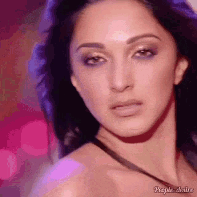 a close up of a woman 's face with a pink background and purple lights behind her .