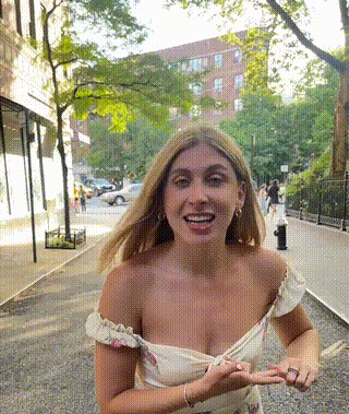 a woman in a white off the shoulder dress is walking down a street .