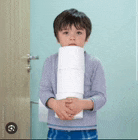 a young boy is holding a roll of toilet paper .
