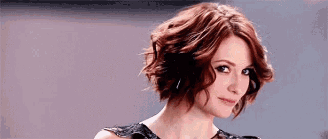a woman with short red hair is wearing a black dress .