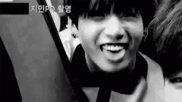 a black and white photo of a young man smiling while holding a tablet .