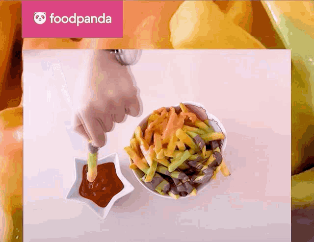 a person dipping french fries in ketchup with a foodpanda logo in the background