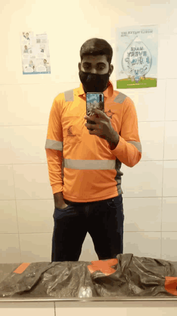 a man wearing a mask takes a selfie in front of a sign that says safety week
