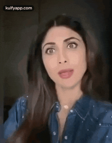 a close up of a woman 's face with a denim shirt on and a necklace .