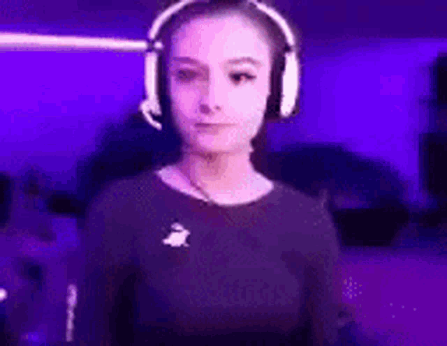 a woman wearing headphones is standing in front of a purple background .