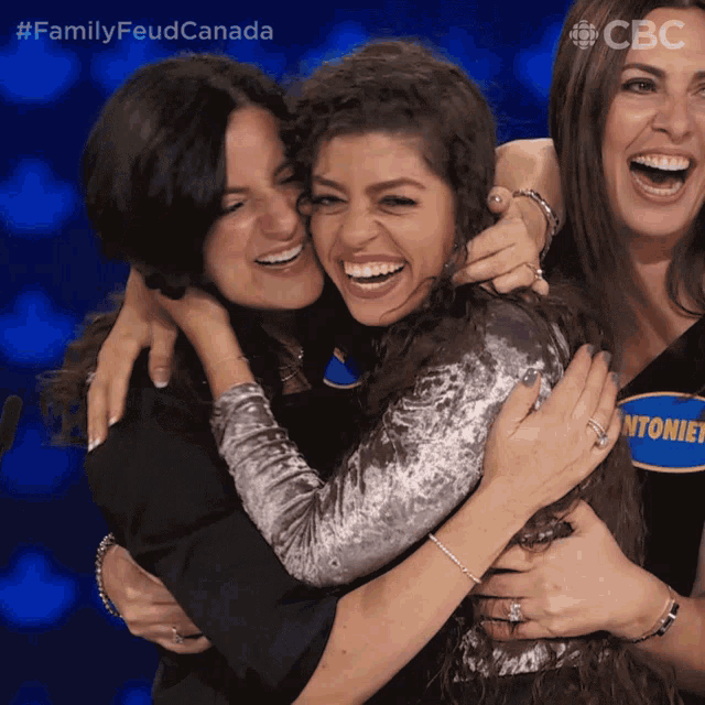 three women hugging each other with the words family feud canada on the bottom right