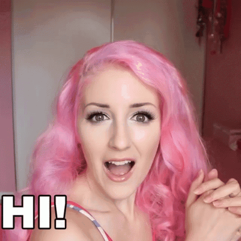 a woman with pink hair says hi and holds her hands up