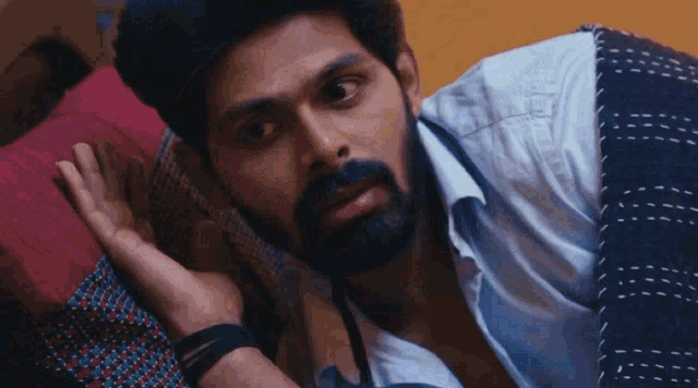 a man with a beard is laying down with his hand on his face