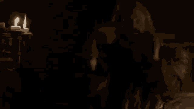 a man with a beard is standing next to a woman in a dark room with two candles .