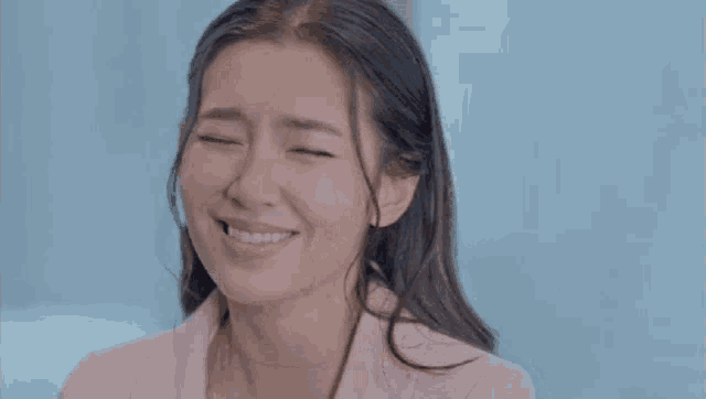 a woman in a pink jacket is smiling with her eyes closed