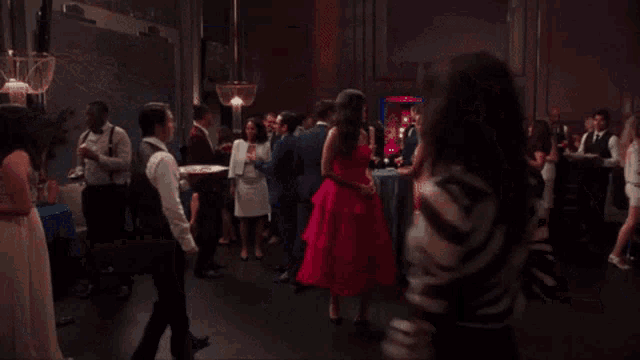 a woman in a red dress is standing in a crowded room .