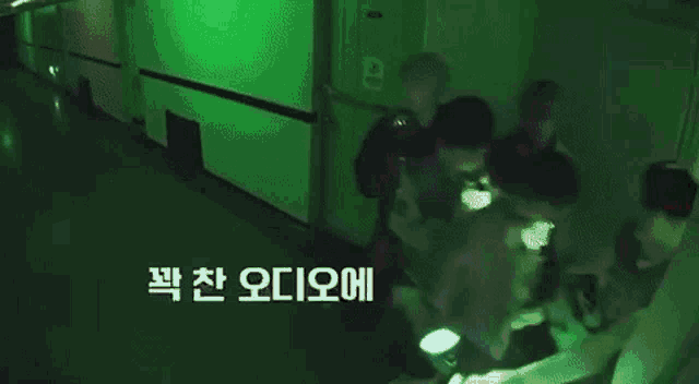 a group of people are standing in front of a green light .