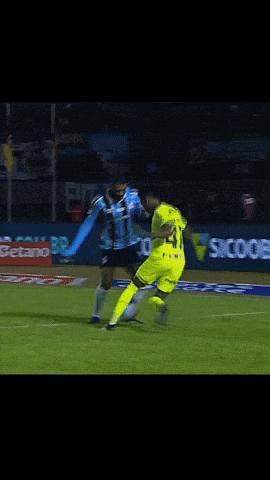 a soccer player kicks a ball in front of a betano ad