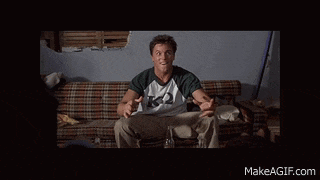 a man is sitting on a couch wearing a shirt with the letter k on it
