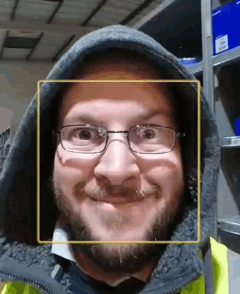 a man wearing glasses and a hood is smiling