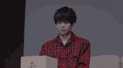 a man in a red plaid shirt is covering his face