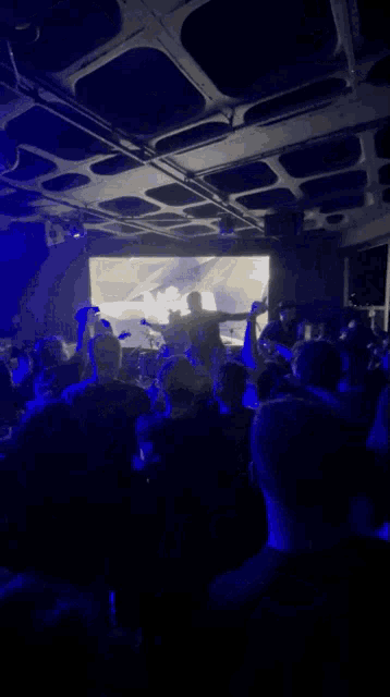 a crowd of people are gathered in a dark room with a large screen behind them that says nasa