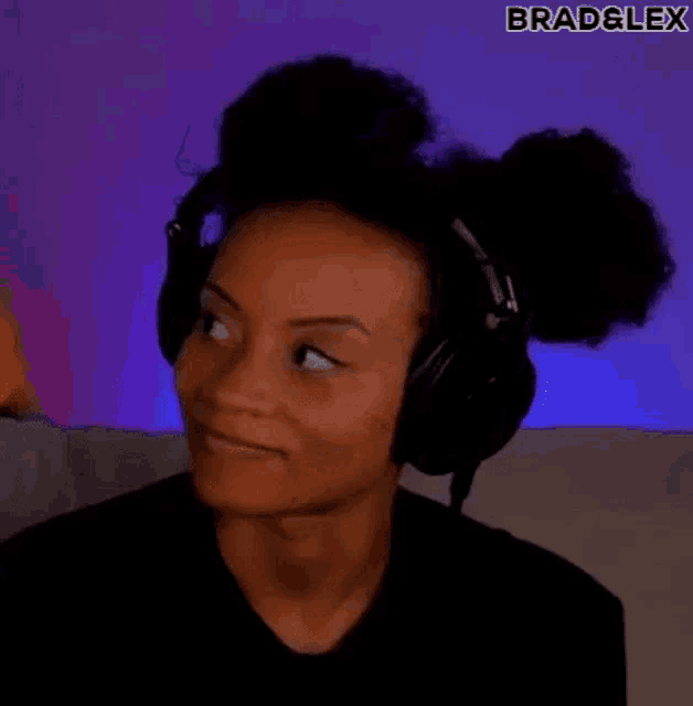 a woman wearing headphones is sitting on a couch and making a funny face .