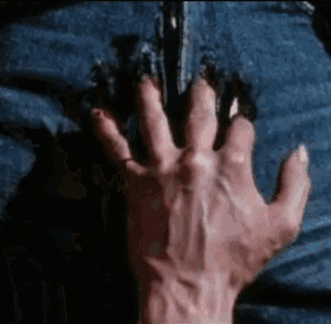 a close up of a person 's hand with sharp claws on their jeans .